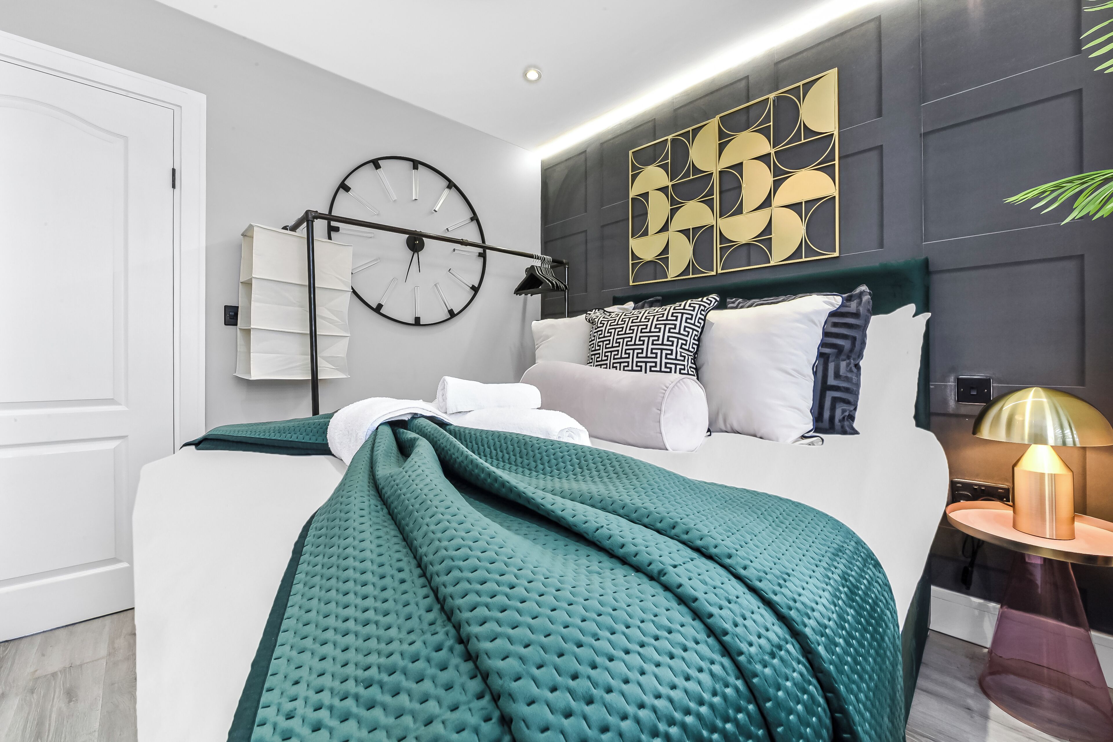 Ein modernes Schlafzimmer mit einem großen Bett, einer Wanduhr und einer Zierleiste.