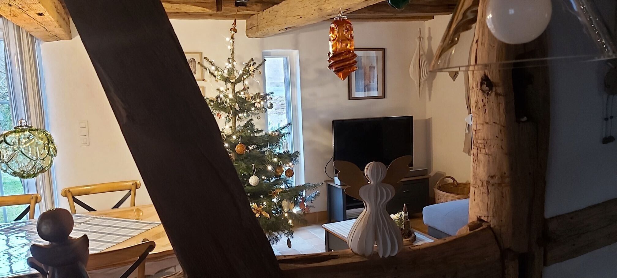En hyggelig stue med trælofter, et juletræ, en pejs og et fjernsyn.