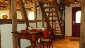 Una mesa de madera con sillas, un mantel rojo y una escalera apoyada en una pared.