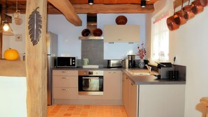 Una cocina moderna con electrodomésticos integrados, vigas de madera en el techo y un ventanal con cortinas.