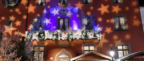 Un bâtiment orné d’une horloge, de décorations en forme d’étoiles et d’un sapin de Noël.