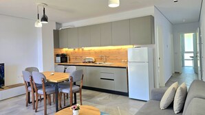 Una cocina moderna con comedor, un refrigerador y un sofá.