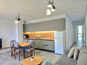 A modern kitchen with a dining area, a refrigerator, and a sofa. - Beachside Apartment 308 (Gjiri Lalzit)
