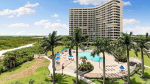 A high-rise hotel with a pool area, palm trees, and a view of the surrounding landscape. - Remodeled Gulf-Front 2BR + Pool (Marco Island)