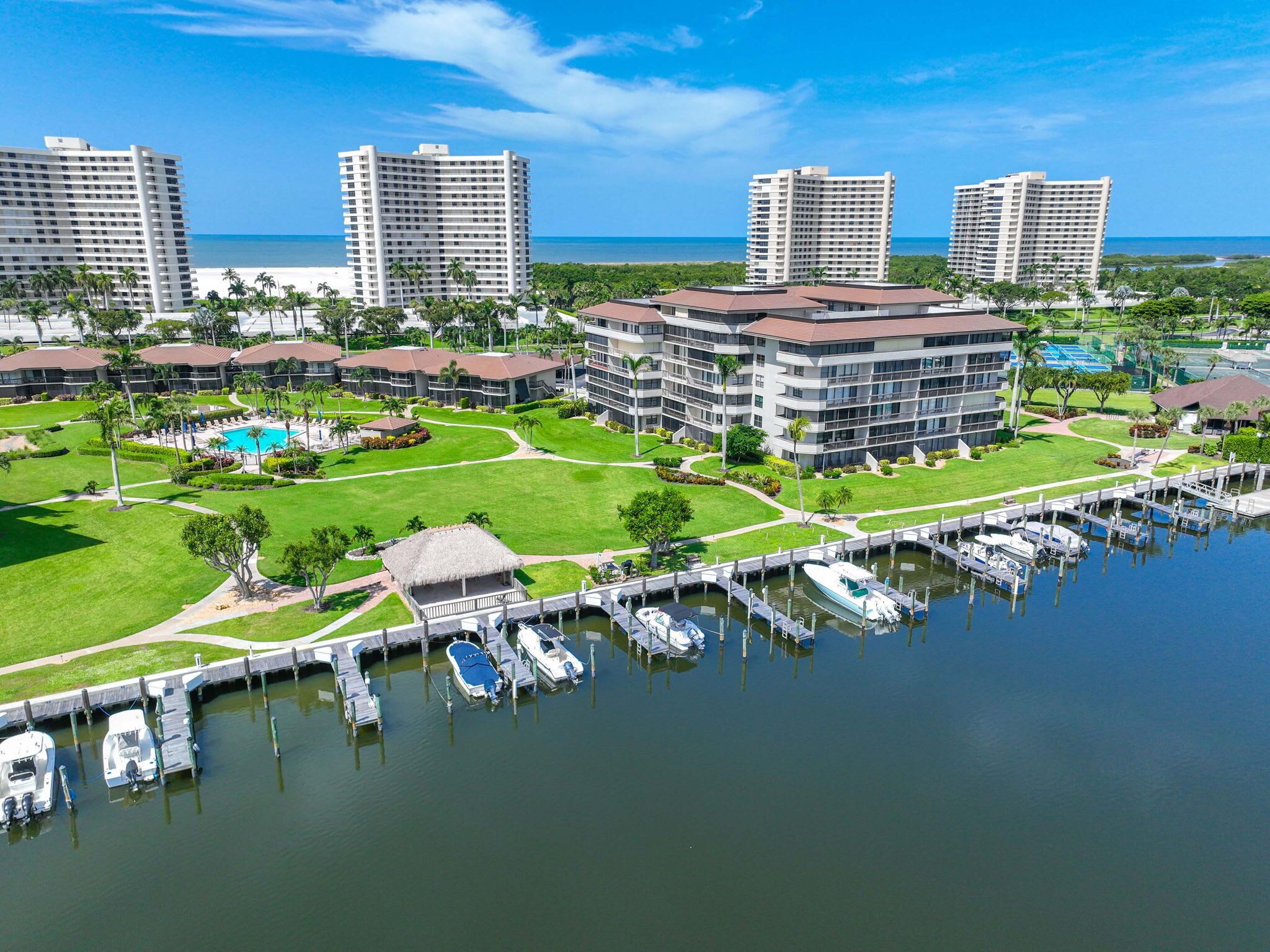 Un complexe hôtelier comprenant plusieurs immeubles de grande hauteur, un port de plaisance avec des bateaux et un vaste espace vert bien entretenu.