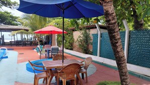 A pool area with a table and chairs, a red umbrella, and a blue umbrella. - Casa en Las Piedronas - piscina privada - AC - BBQ (Sonsonate Department)