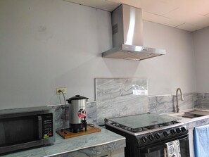 A kitchen with a microwave, a stove, a sink, and a stainless steel range hood.