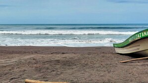 A beach with a green boat on the sand. - Casa en Las Piedronas - piscina privada - AC - BBQ (Sonsonate Department)
