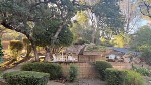 A garden with a paved walkway, a brick wall, and a seating area with chairs. - Beautiful Lake House Minutes from Lake Oroville (Oroville)
