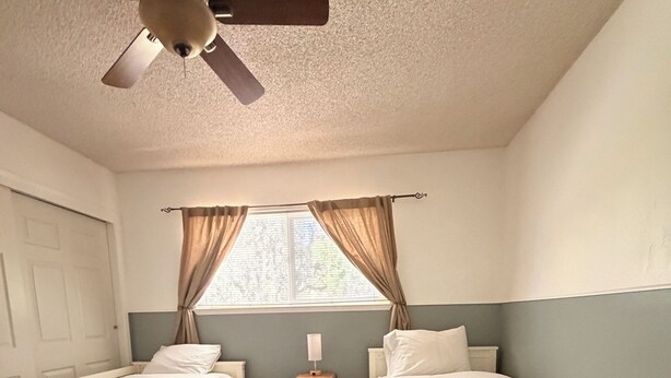 A bedroom with two single beds, a ceiling fan, a nightstand, and a window with curtains. - Beautiful Lake House Minutes from Lake Oroville (Oroville)