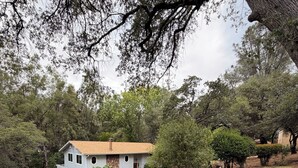 Una propiedad residencial con entrada pavimentada, una casa de techo a dos aguas y zonas verdes a su alrededor.