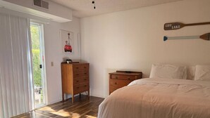 Un dormitorio con cama, cómoda de madera y puerta que da a un balcón.
