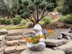 Eine Steinskulptur mit einem Teleskop und Blumen in einer Gartenanlage.