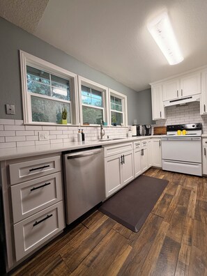 A modern kitchen with white cabinetry, a built-in dishwasher, a double oven, and a window above the sink. - Beautiful Lake House Minutes from Lake Oroville (Oroville)