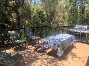 Un patio al aire libre con una mesa, sillas y una parrilla.