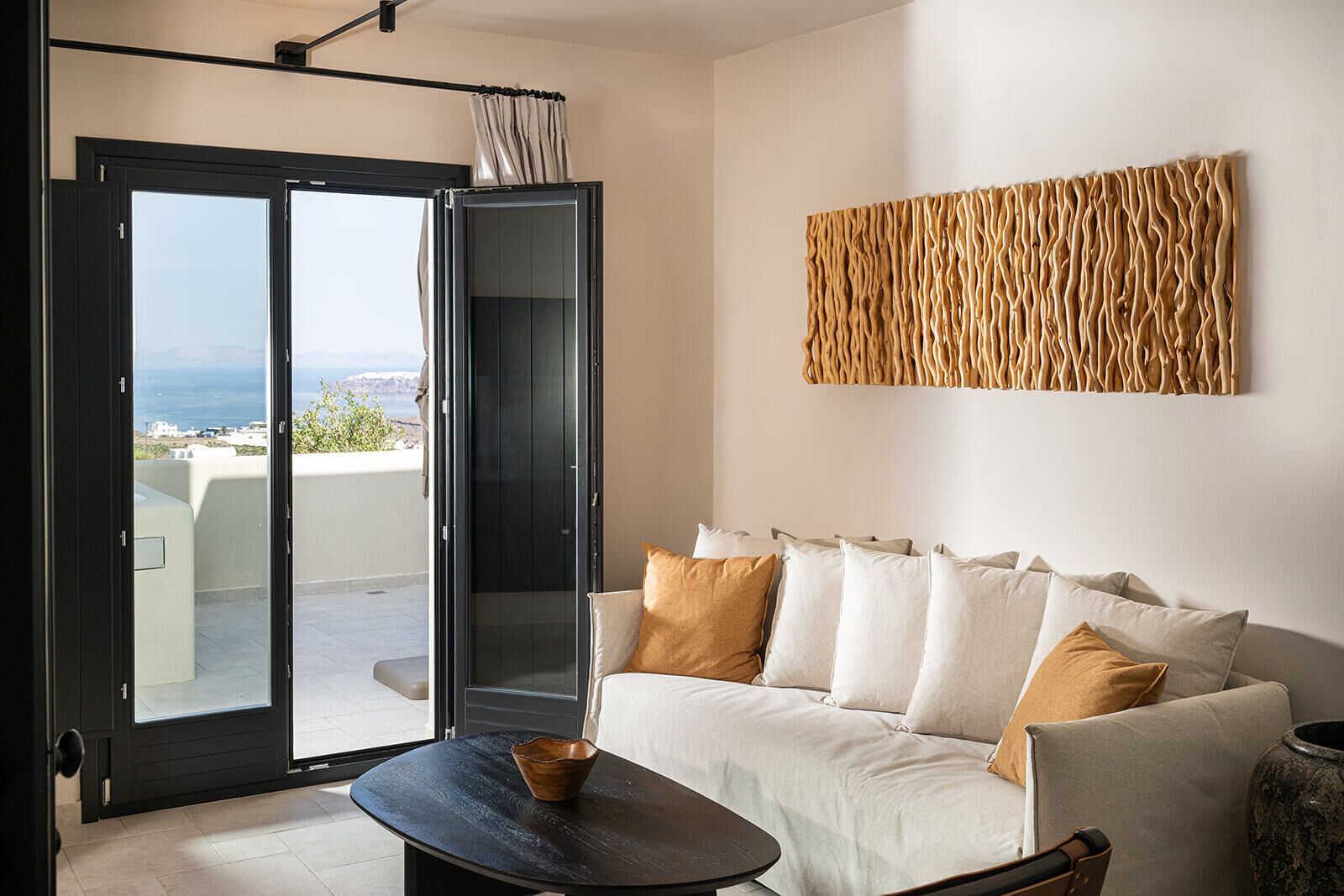 A modern living room with a sofa, a coffee table, and a view through a sliding glass door to an outdoor terrace.