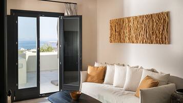 A modern living room with a sofa, a coffee table, and a view through a sliding glass door to an outdoor terrace.
