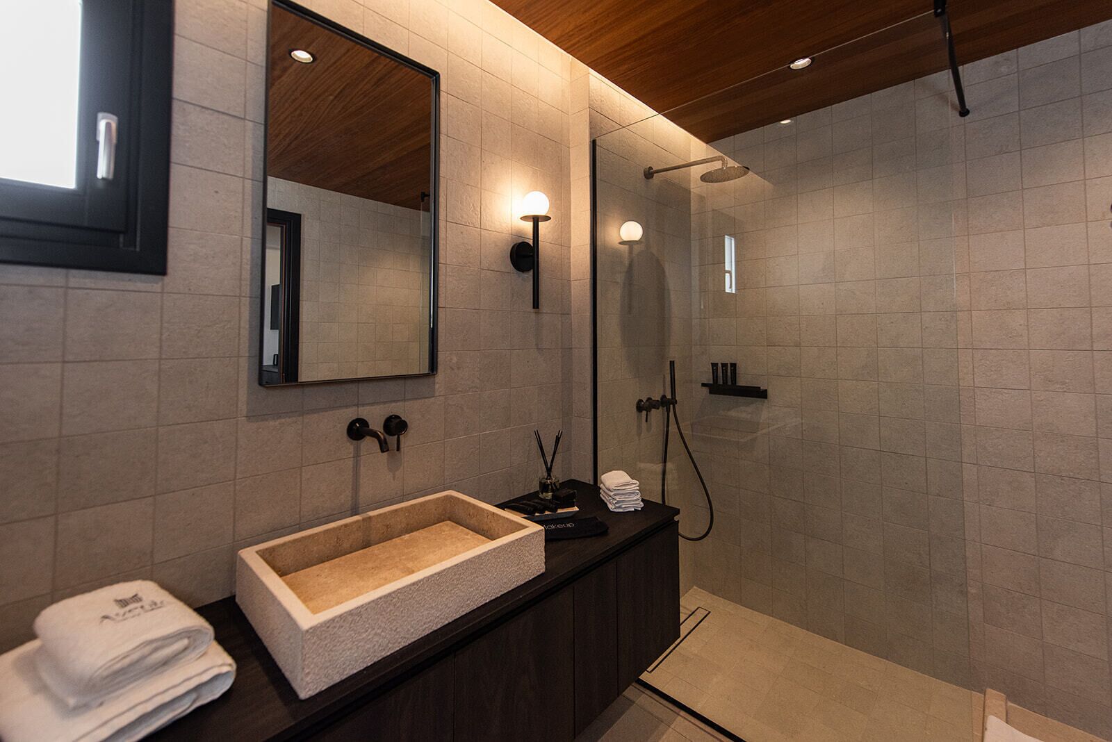 A modern bathroom with a large mirror, a rectangular sink, and a shower area.