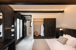 A modern bedroom with a large bed, a wardrobe, and a walk-in closet. - Avento Luxury Suites (Santorini)