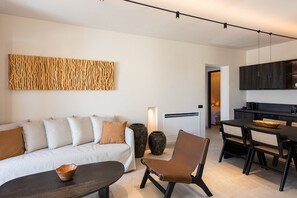 Un saló modern amb un sofà, una taula de centre i una zona de menjador amb cadires i una taula.