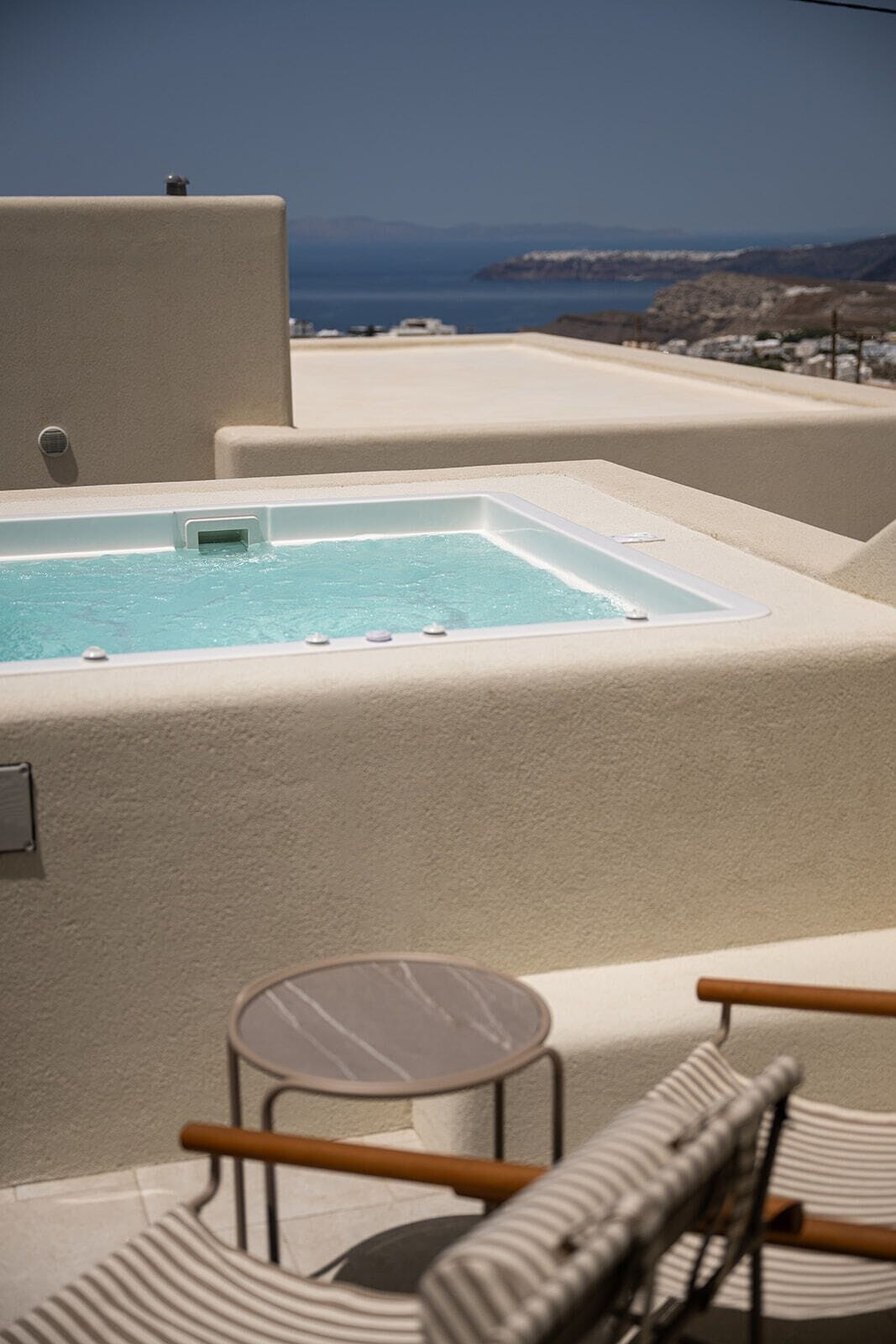 A rooftop pool area with a hot tub and seating.