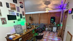 Una zona de bar con mostrador de madera, taburetes y un letrero de neón.
