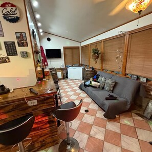 Un espacio de sala acogedor con barra, sofá y televisor.