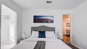 A hotel room with a large bed, a cityscape painting, and a view of the city through the window. - Homey & Spacious 4-bedroom house in fabulous Austin neighborhood (Austin)