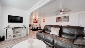 A modern living room with a leather sofa, a white coffee table, and a dining area in the background. - Homey & Spacious 4-bedroom house in fabulous Austin neighborhood (Austin)