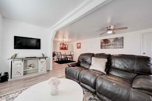 A modern living room with a leather sofa, a white coffee table, and a dining area in the background. - Homey & Spacious 4-bedroom house in fabulous Austin neighborhood (Austin)