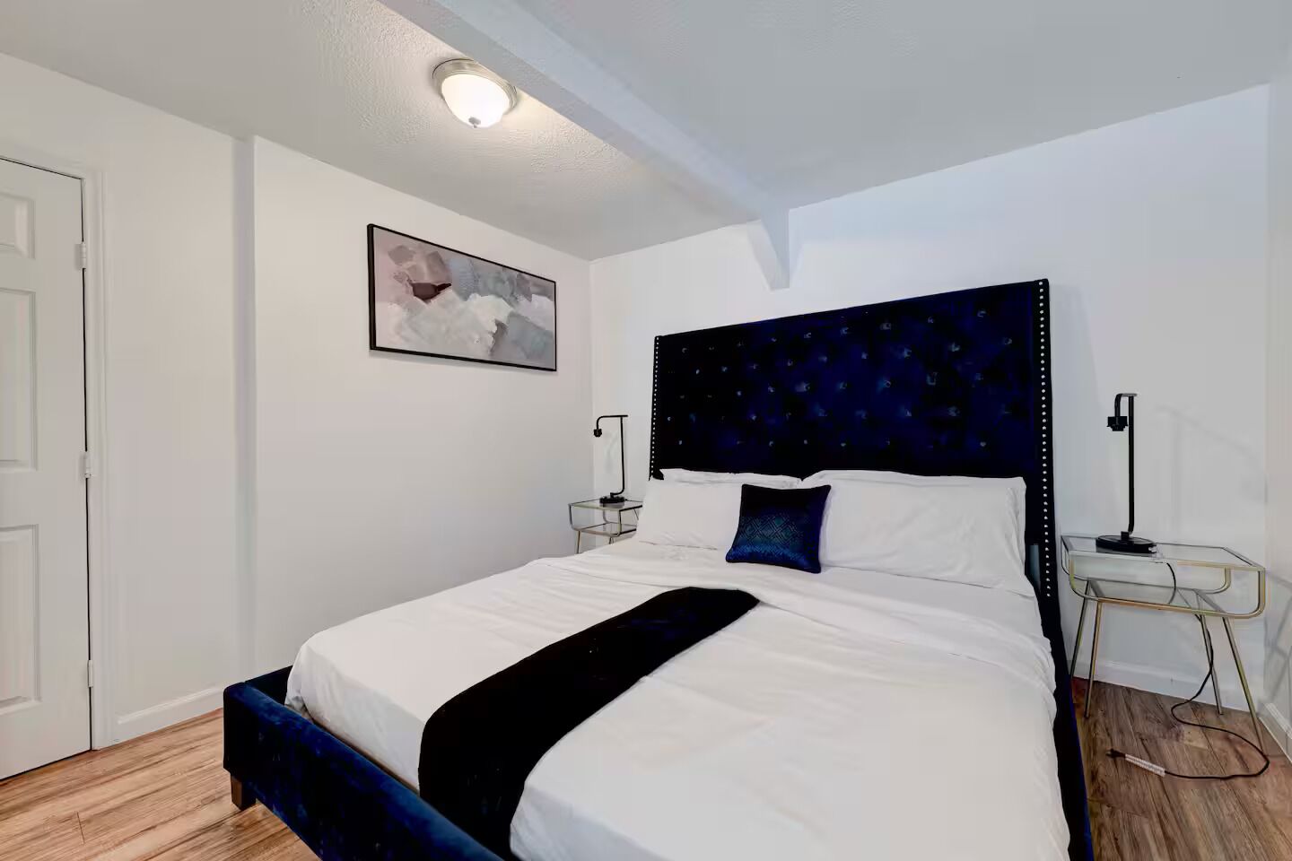 Une chambre d’hôtel avec un lit, une table de chevet, une lampe de chevet et un tableau accroché au mur.