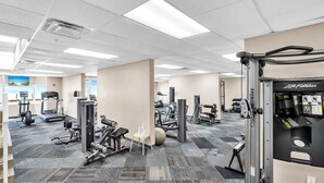 Uma academia com diversos equipamentos de exercício, incluindo esteiras, aparelhos de musculação e pesos livres.
