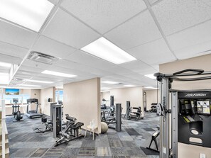Ein Fitnessstudio mit verschiedenen Trainingsgeräten, darunter Laufbänder, Kraftgeräte und Kurzhanteln.
