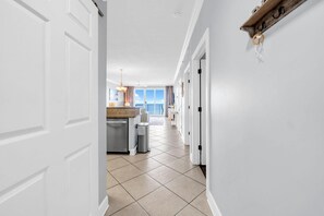 A hallway leading to a kitchen with a view of the outdoors. - Twin Palms 2204 (Panama City Beach)
