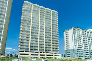 Ein mehrstöckiges Hotel mit Balkonen, einer Tiefgarage und blauem Himmel.