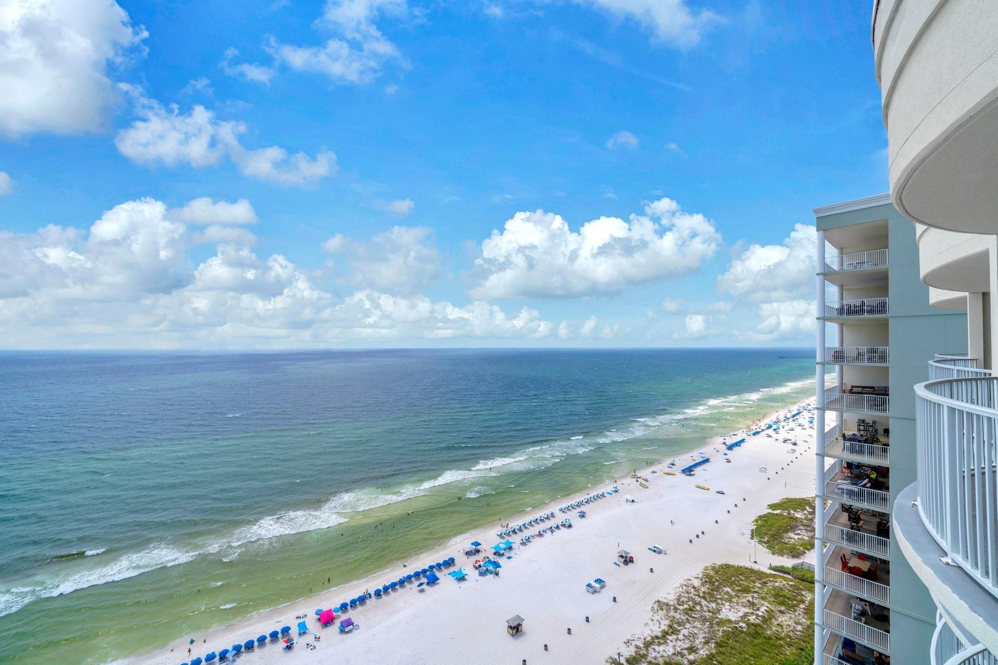 A beach with a view of the ocean and a building with balconies.