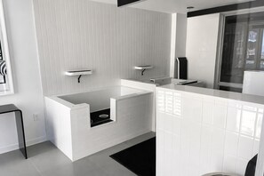 Een moderne badkamer met een witte betegelde muur, een inbouwbad en een grote spiegel.