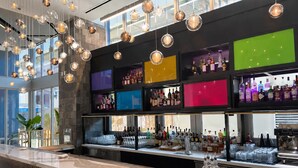 Un área de bar con lámparas esféricas colgantes, estantes con botellas de licor y una encimera de mármol.