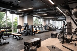A gym with various exercise equipment, large windows, and a view of palm trees. - Comfy Condo-Hotel in Downtown Miami (Miami)