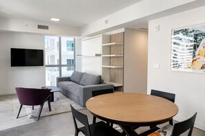 A modern office space with a grey sofa, a round wooden table, and black chairs. - Comfy Condo-Hotel in Downtown Miami (Miami)