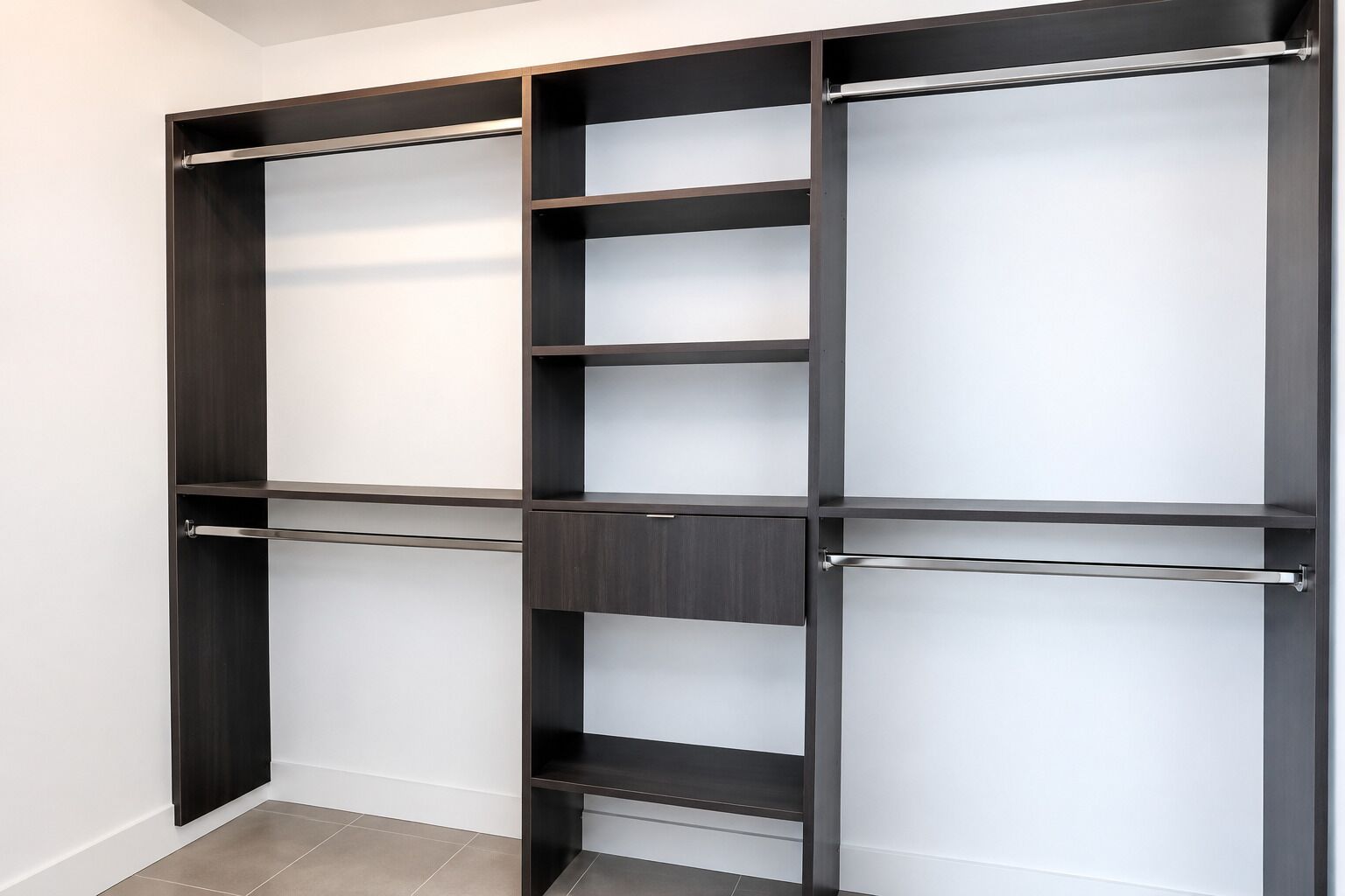 A modern closet with multiple shelves and hanging rods.