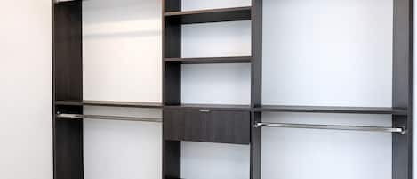 A modern closet with multiple shelves and hanging rods.