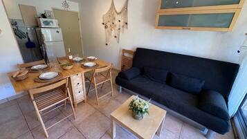 Um espaço compacto com mesa de jantar, cadeiras, sofá, pequena mesa de centro e cozinha equipada.