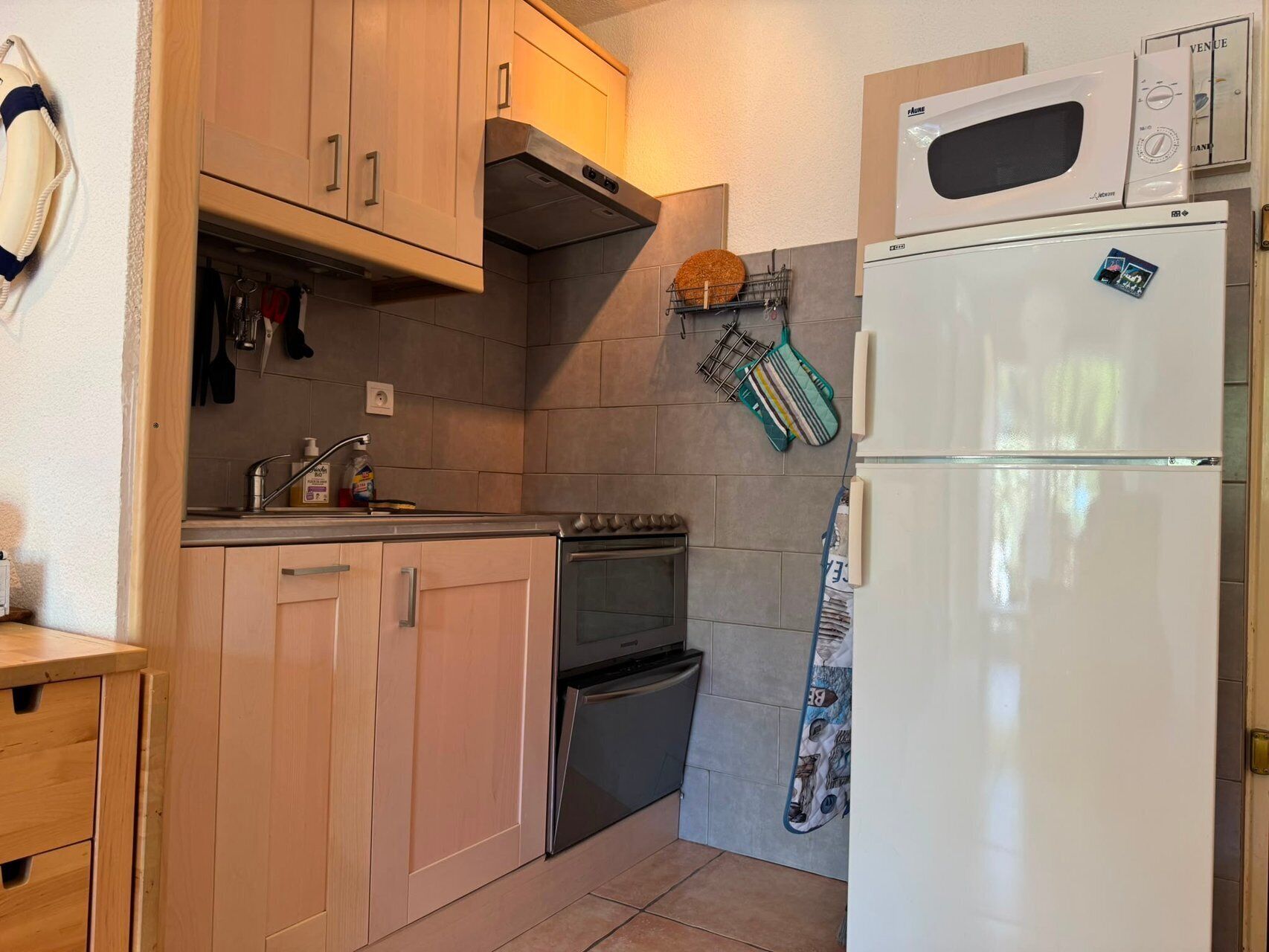 Une cuisine de taille réduite, dotée de meubles en bois, d’une cuisinière, d’un four à micro-ondes et d’un réfrigérateur.