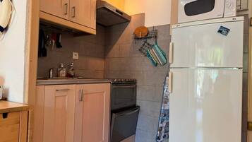 Une cuisine de taille réduite, dotée de meubles en bois, d’une cuisinière, d’un four à micro-ondes et d’un réfrigérateur.