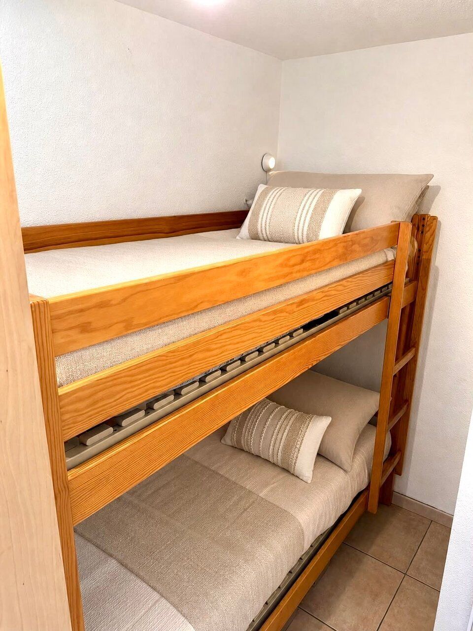 Un lit superposé avec une structure en bois et une literie de couleur beige.