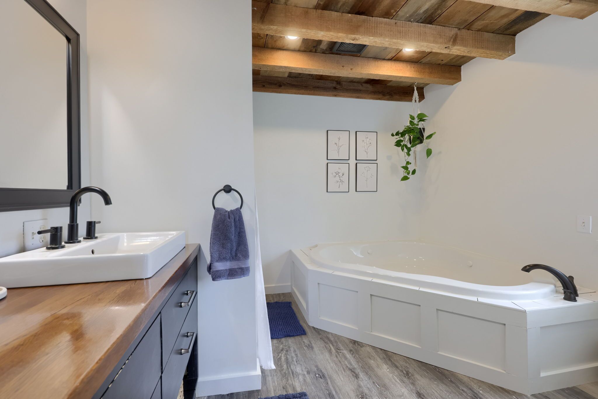Un baño moderno con tocador de madera, una bañera grande y un espejo.