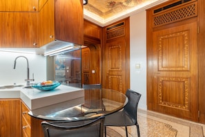 A modern kitchen with wooden cabinetry, a glass-top dining table, and a black chair. - Spazio Santana (Milano)