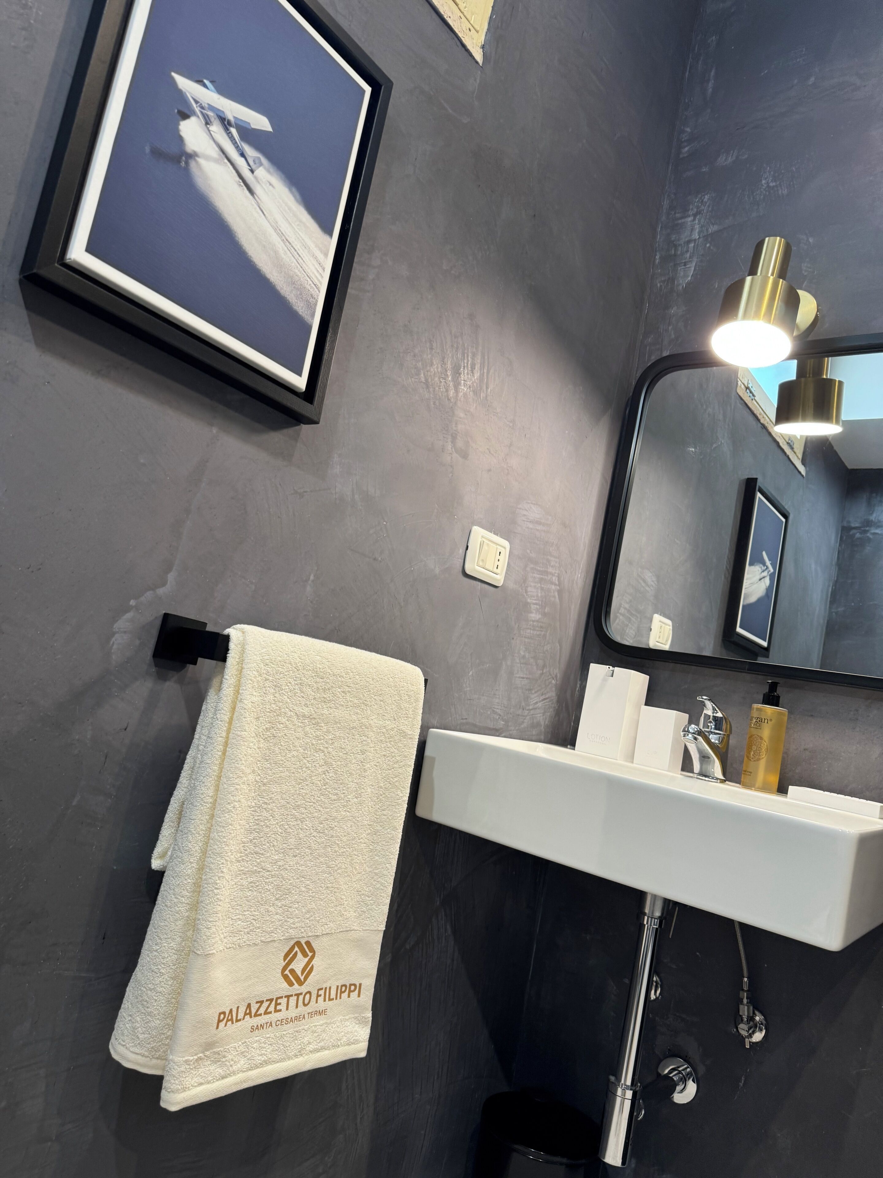 Ein Badezimmer mit Handtuch, einem gerahmten Bild, einem Waschbecken und einem Spiegel.