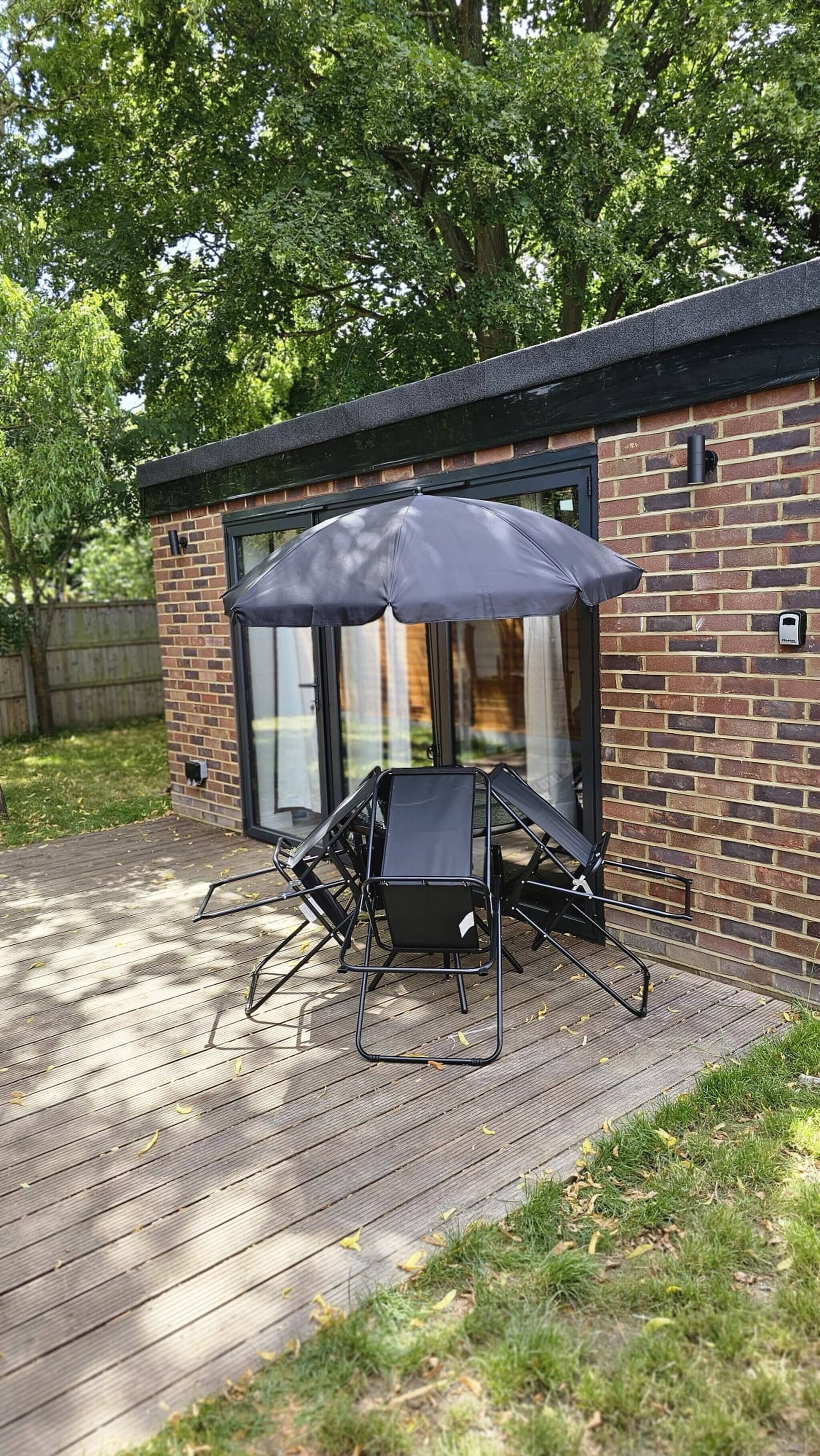 A patio with a grill, outdoor furniture, and a brick building with large windows.